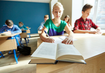 group of students with books writing school test