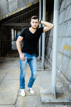 Handsome man against wall wearing jeans and  black T-shirt