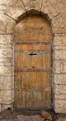 Fototapeta na wymiar Old wooden door in the stone wall
