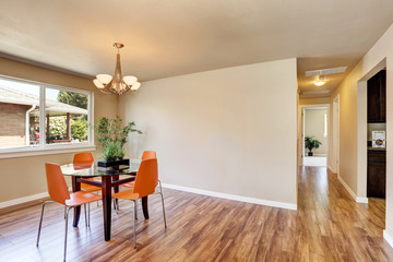 Modern dining area with orange chairs and glass table.