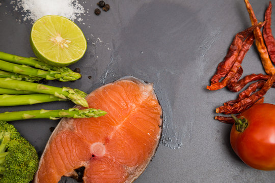 Flat lay of raw salmon fillet and ingredients for cooking on a d
