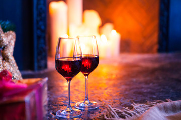 Two glass with red wine on Christmas tree and fireplace backgrou