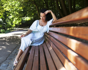 beautiful woman in a blue dress sitting on a bench