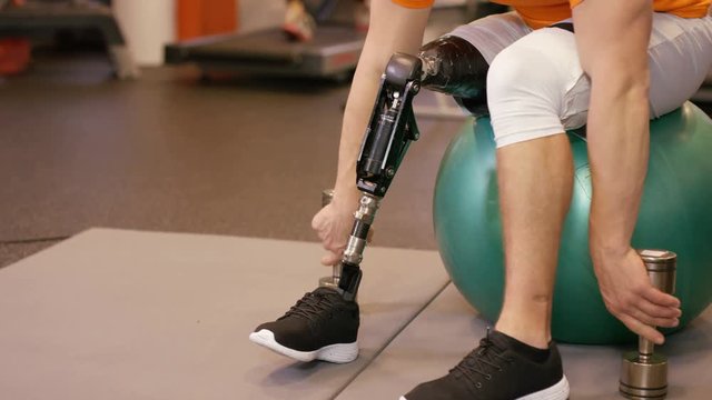  Muscular man with prosthetic leg working out with weights at the gym