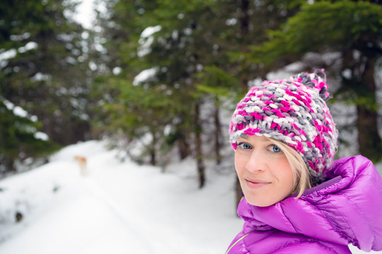 Happy woman walking in winter forest with dog. Girl hiking in white winter woods.