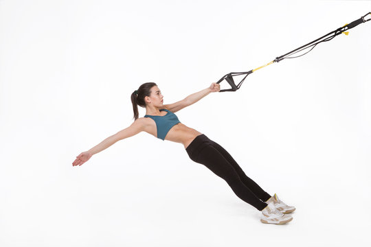 Picture of fitness trainer posing for photographer while training with suspension trainer sling or suspension straps. TRX concept.