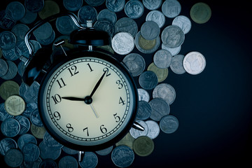 saving time, Alarm clock with coins isolated on black background.