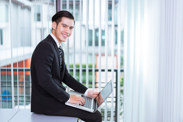 Fototapeta premium Portrait Of A Handsome Young Happy Man Using laptop in office