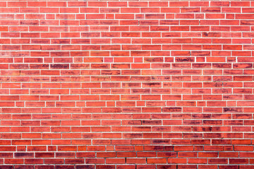 Bright red brick wall background with dark stains