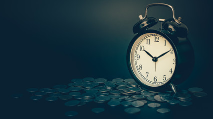 saving time, Alarm clock with coins isolated on black background. with vintage filter