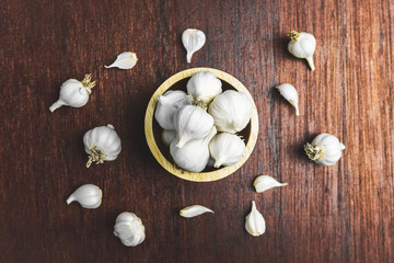 White garlic in the wooden bowl on wood floor