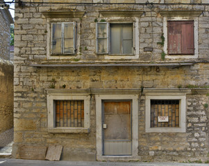 Fototapeta na wymiar An historic old derelict building in Skradin old town, Sibenik-Knin County, Croatia. The sign on the window announces that the building is for sale. 