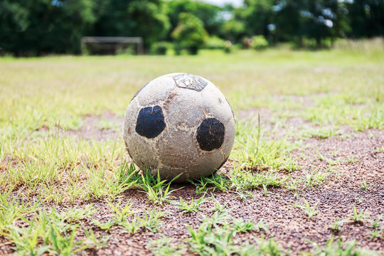 Old football on the field and small gravel