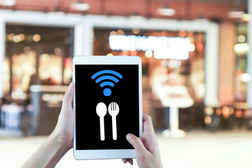 tablet in hand wireless wi-fi spoon eating icon on blurred restuarant background