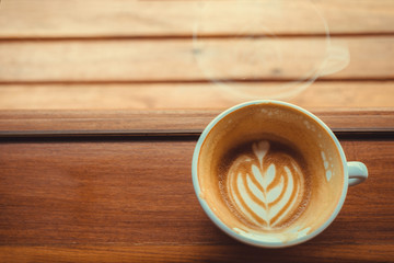 heart drawing on latte art coffee cup on a side of the window in