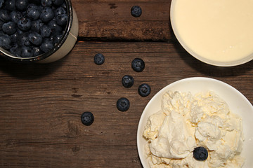 Cottage cheese, sour cream and bilberry on old wooden table.