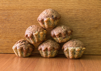 Pyramid of bicolor muffins with chocolate, poppies and walnuts on table.