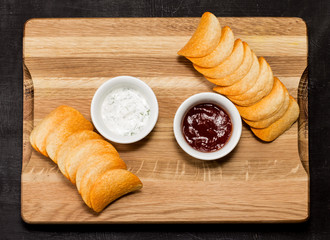 Potato chips with sauce on a black wooden background, soft focus, horizontal, top view