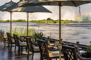 Beautiful Swimming Pool with deck chairs and pottery and Zambezi River in the background