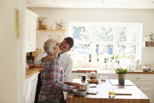 Male couple kissing before one leaves for work, side view