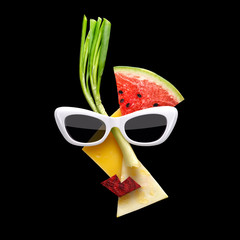 Fruity Picasso / Quirky food concept of Picasso style female face in sunglasses made of fresh fruits on black background.