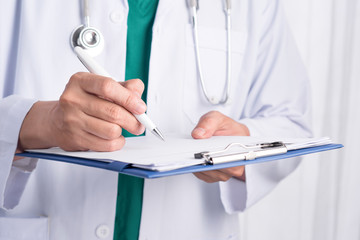 Cropped image of male doctor in medical office writing prescript