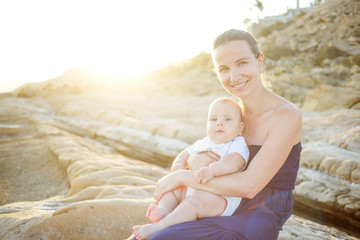 Mother and her son have great time at the seashore at sunset