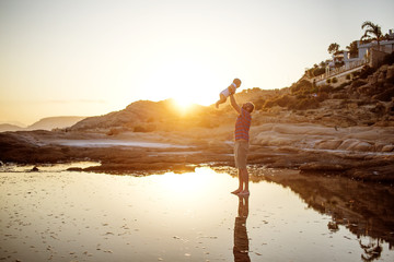 Father and his son have fun at the sea beach at the sunset