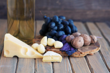 Cheese plate on the wooden board with grape, walnut, honey and milk on black