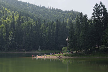 Lake Synevyr.  Morning in reserve Sinevir. Tourists are contemplateing the lake and its surroundings