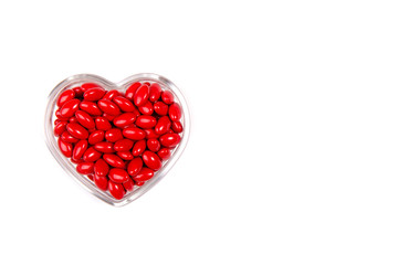 Red pills in the shape of a heart isolated on white