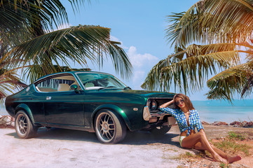 Young attractive model is sitting near the retro car at the beach