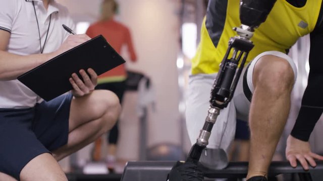  Disabled athlete at the gym puts on prosthetic leg to prepare for workout