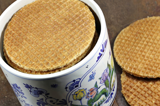 traditional Dutch syrup waffles in an original Delftware container on wooden background