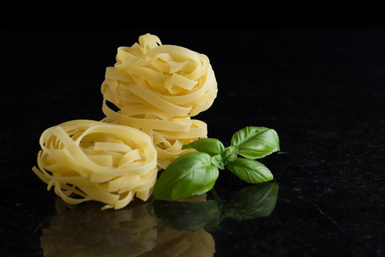 Pasta Tagliatelle, parmesan arranged on marble table. Delicious dry uncooked ingredients for traditional Italian cuisine dish. Raw closeup background. Top view. Copy space
