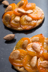 Pie with apricot. Traditional french tart with fruits on dark marble background. Decorated almonds and mint leafs. Delicious dessert with copy space closeup.
