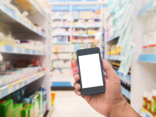 Fototapeta na wymiar Hand with smartphone on blurred pharmacy store