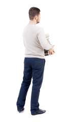 A man carries a heavy pile of books. back view. Rear view people collection.  backside view of person.  Isolated over white background. The bearded man in a white warm sweater holds a lot of books