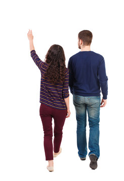 Back view of walking young couple (man and woman) pointing. Rear view people collection. backside view of person. Isolated over white background. Swarthy girl and the bearded man walk away seeing