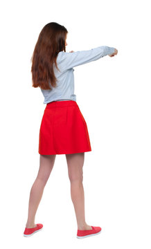 skinny woman funny fights waving his arms and legs. Isolated over white background. Long-haired brunette in red skirt has a hand.