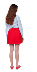 back view of standing young beautiful  woman.  girl  watching. Rear view people collection.  backside view of person. Long-haired brunette in red skirt looks down sideways.  