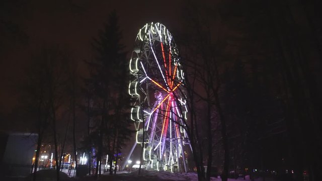 Ferris wheel rotating at amusement park under dark night sky