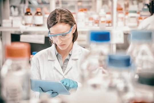 Chemist wearing safety glasses and using tablet pc