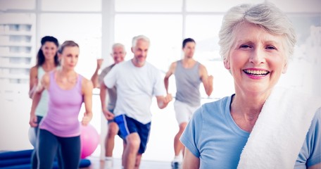 Senior woman with people exercising in fitness studio - obrazy, fototapety, plakaty