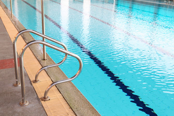 Swimming pool with metal handrail stair