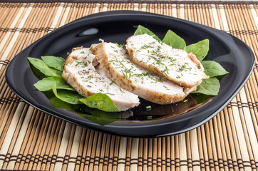 Three slices of roasted chicken on a black plate