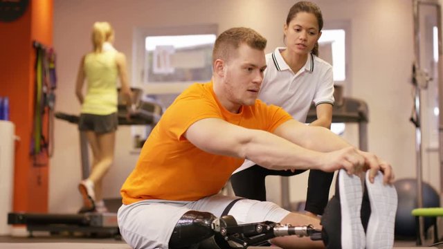  Man with prosthetic leg working out at the gym with personal trainer