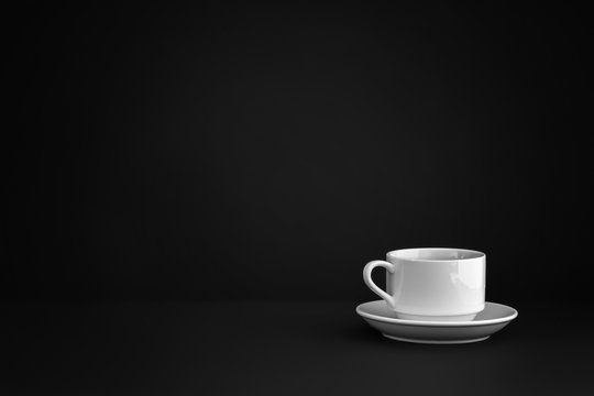 White empty ceramic mug from cafe with a saucer are in the corner of a black background.