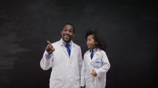  Academic man & woman writing math formulas on blackboard & discussing ideas