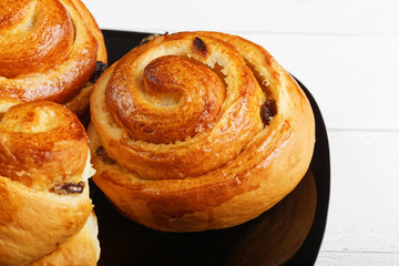 Buns with raisin in a black plate on white table